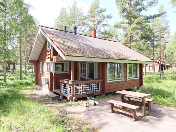 A cabin with a porch, a grill, and a picnic table.