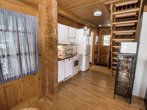 A wooden interior with a kitchen area, including cabinets, a stove, and a refrigerator.