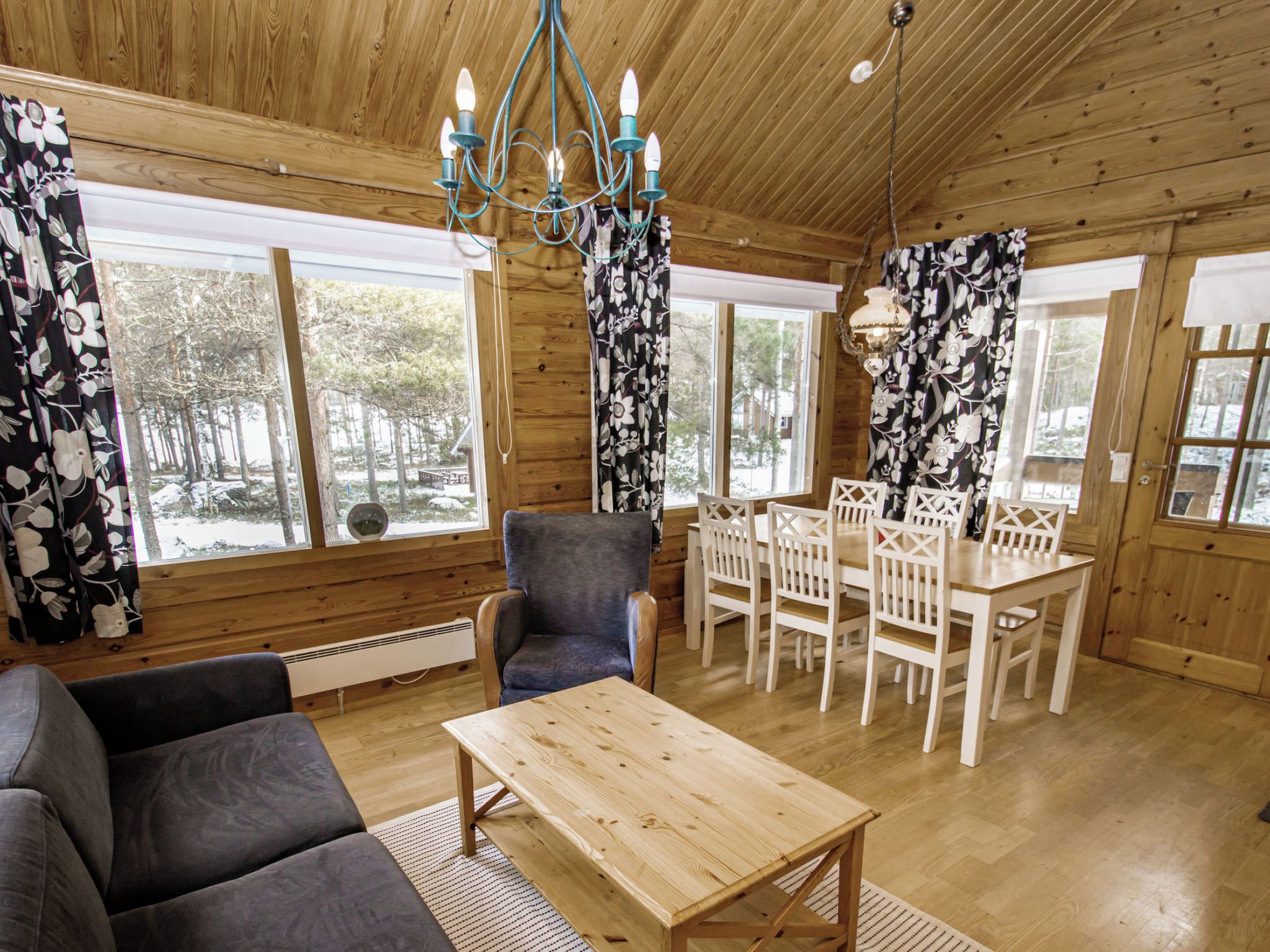L’intérieur d’un chalet en bois, avec un canapé, une table à manger, des chaises et un lustre.