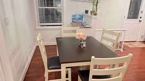 Uma sala de jantar com mesa de madeira escura, cadeiras brancas e um ventilador de teto.
