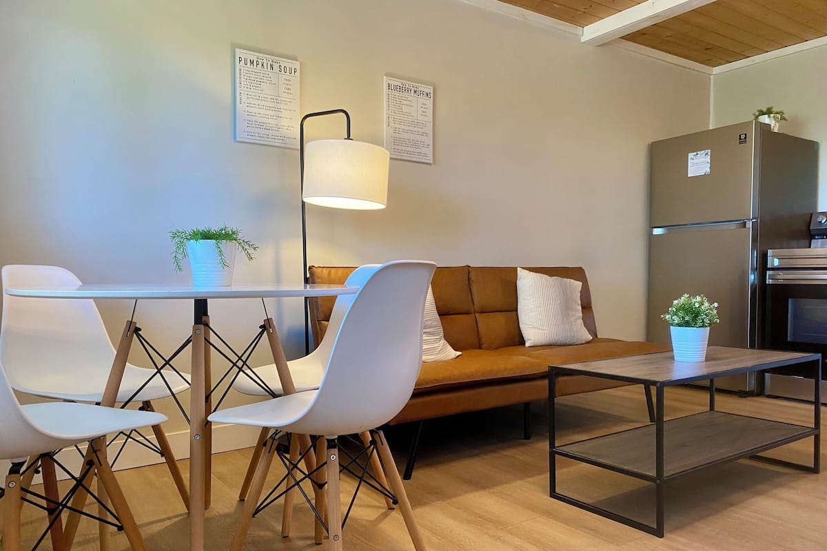 A modern kitchen with a refrigerator, oven, and a dining area with chairs and a table.