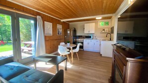 A modern cabin interior with a dining area, kitchen, and a seating area with a view of the outdoors. - South Shore Suites (Bayfield)