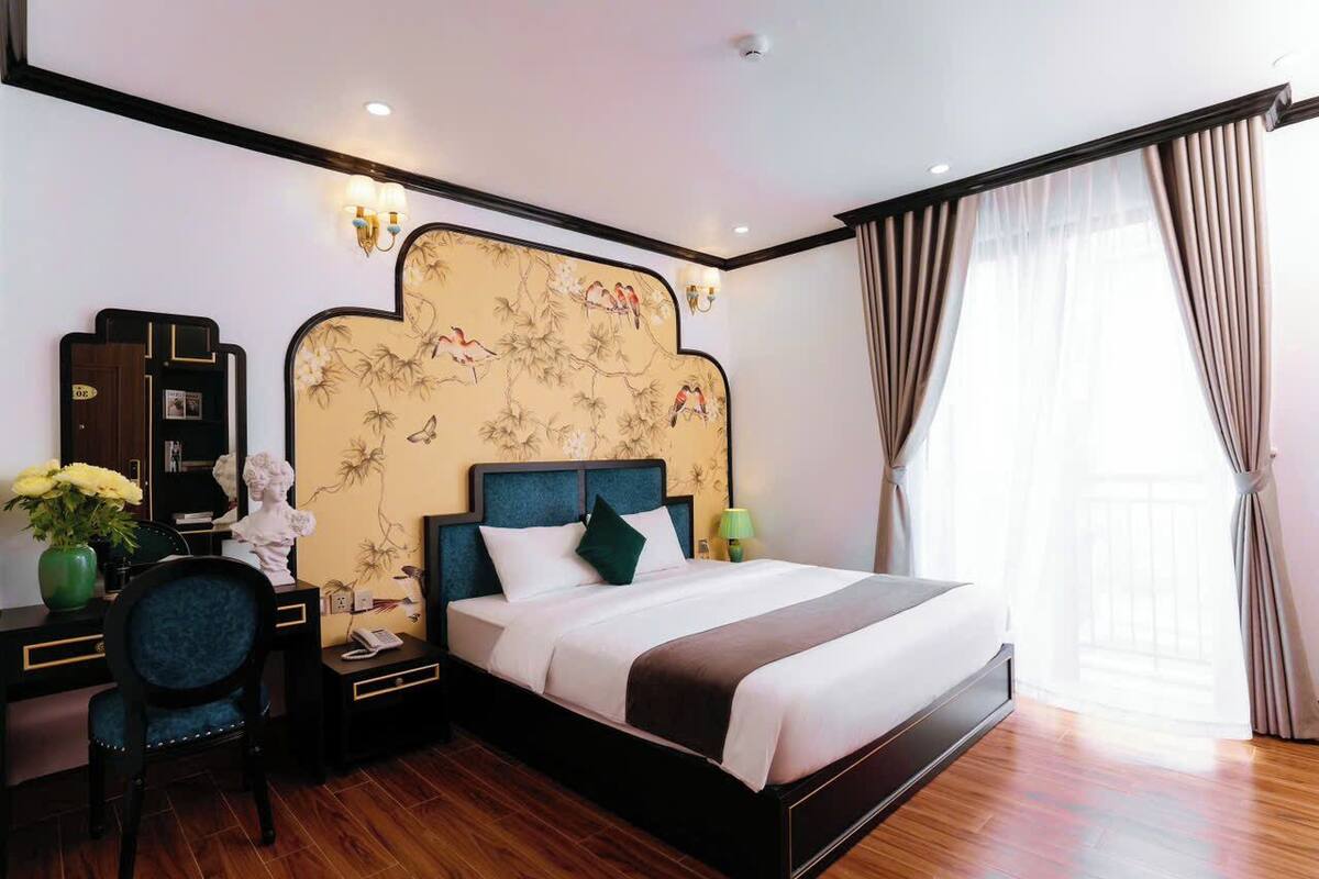 Une chambre d’hôtel comprenant un lit, un bureau, une chaise et un mur décoratif.
