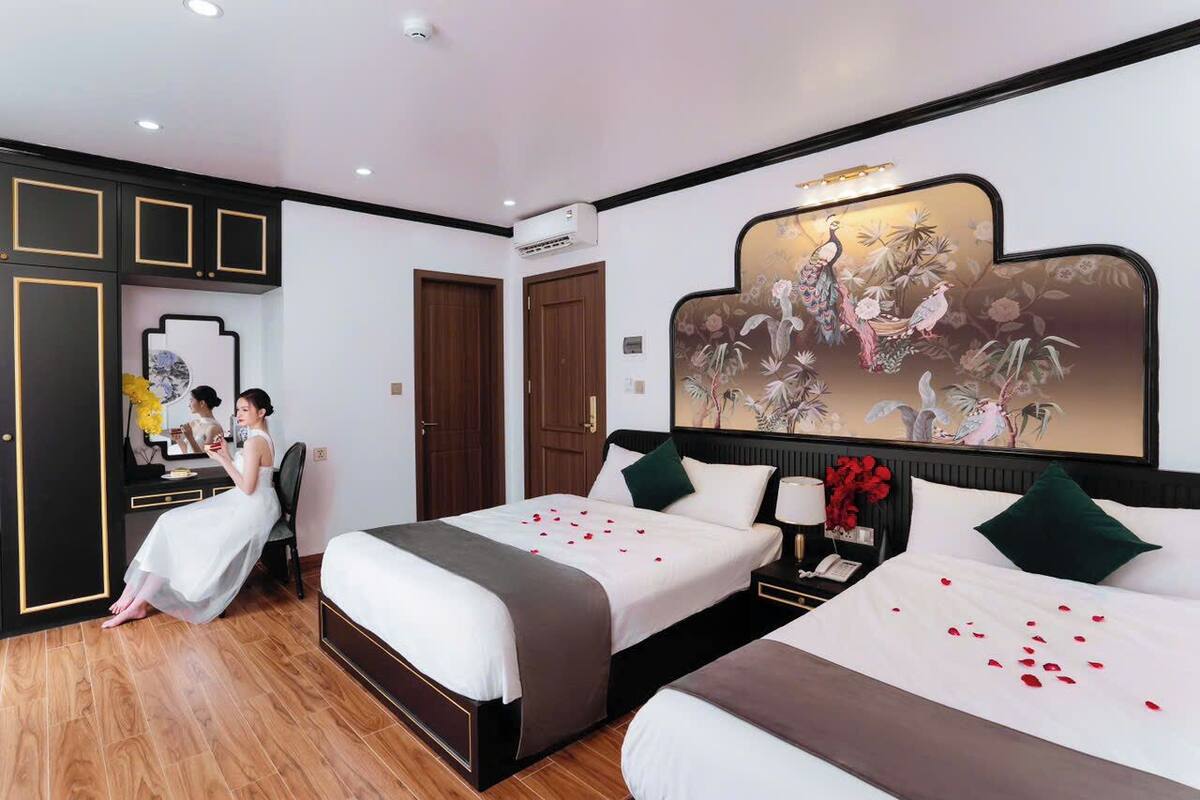 Une chambre d’hôtel avec deux lits, un coin salon, un miroir et un tableau décoratif au mur.