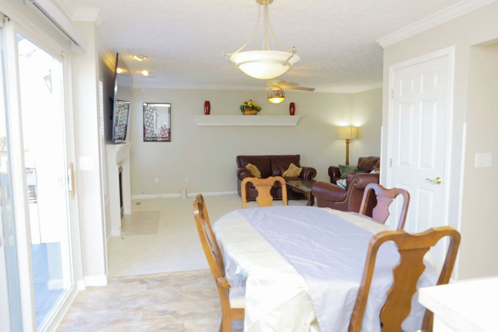 A spacious room with a large bed, a dining table, and a sofa. There is a ceiling fan and a window providing natural light.