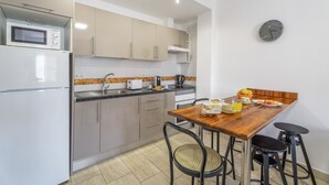 A modern kitchen with a microwave, stove, sink, and a dining area with a wooden table and chairs. - Vacation 'Ifae 3' with Wi-Fi (Guía de Isora)