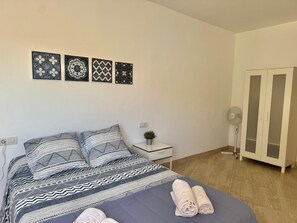 A bedroom with a bed, a nightstand with a plant, a wardrobe, and wall art. - Vacation 'Ifae 3' with Wi-Fi (Guía de Isora)