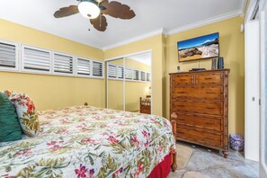 Ein Schlafzimmer mit einem Bett, einem Schminktisch, einem Deckenventilator und einem Bild an der Wand.