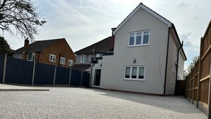 Ein Wohnhaus mit weißer Fassade, einem geneigten Dach und einer Auffahrt mit Kies.