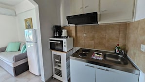 A compact kitchen with a microwave, stove, and cabinets.