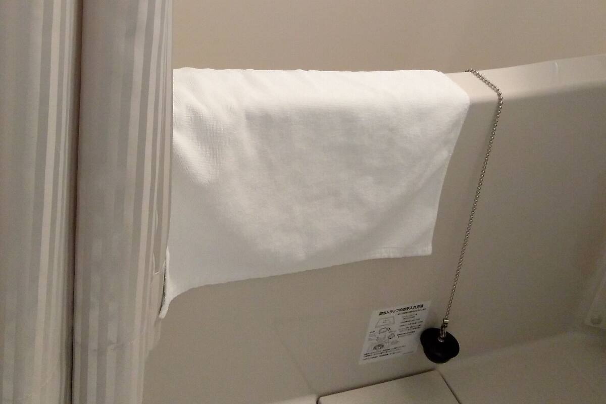 A bathroom with a bathtub, a towel hanging on the side, and a small shelf with a power outlet.