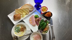 Un plato de desayuno con tostadas, jamón, huevos y verduras.