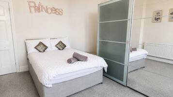 A bedroom with a bed, a wardrobe, a mirror, and a wall decoration.