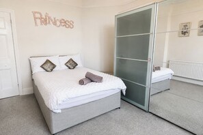 Un dormitorio con cama, armario, espejo y un adorno en la pared.