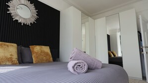 Un dormitorio moderno con una cama grande, un espejo y un armario.