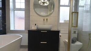 Un baño moderno con una bañera independiente, un lavabo sobre encimera y un inodoro.