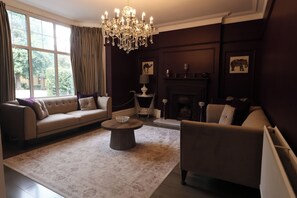 Una sala de estar con sofá, sillón, mesa de centro y chimenea.
