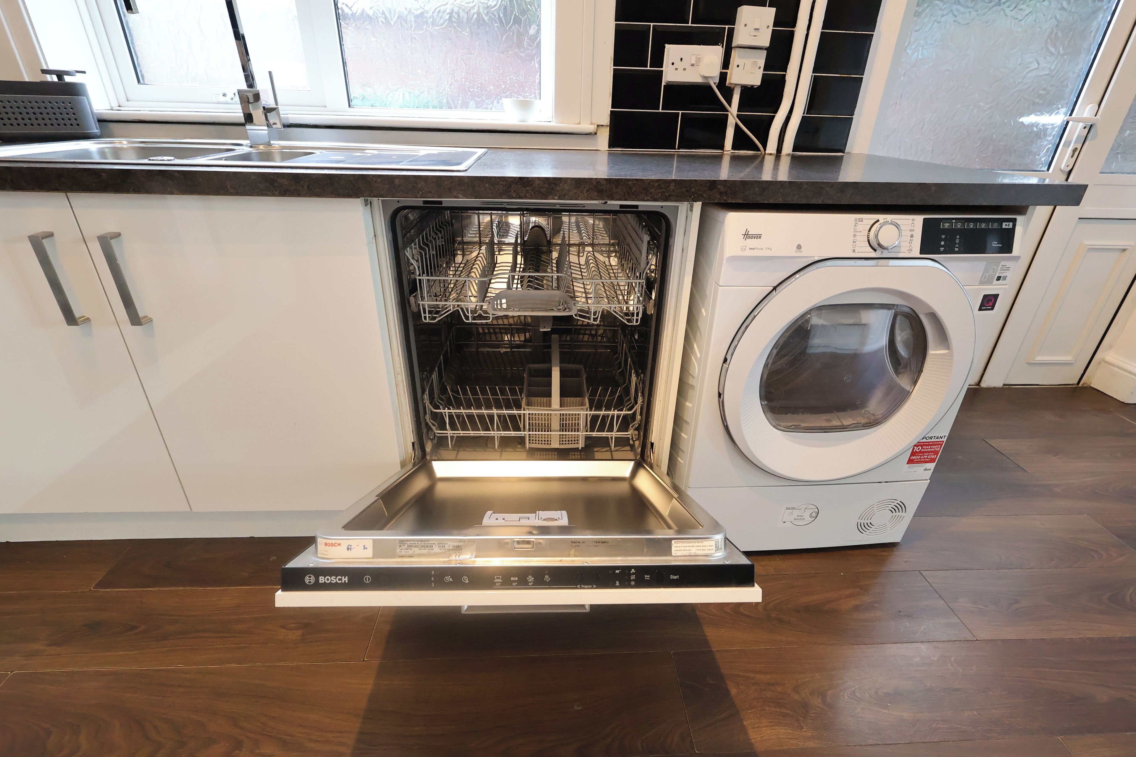 Un lave-vaisselle Bosch installé sous un plan de travail de cuisine, avec un lave-linge intégré.