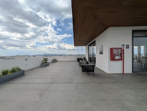 En takterrass med sittplatser, en brandsläckare och utsikt över stadsbilden.