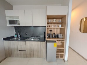 Una cucina compatta con forno a microonde integrato, piano cottura a gas e frigorifero.