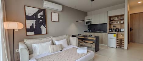 Una habitación de hotel moderna con una cama grande, kitchenette y comedor.
