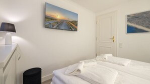 A bedroom with a bed, a lamp, a trash bin, and two paintings on the wall. - An der Seedüne, App. Carpe diem - "Relax in our vacation apartment at (Unknown)