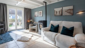A cozy living room with a sofa, a fireplace, and a dining area. - Beluga with parking and shared pool by Interhome (De Haan)