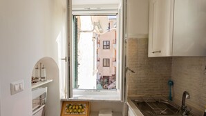 A compact kitchen with a window, white cabinets, a sink, and a small countertop.