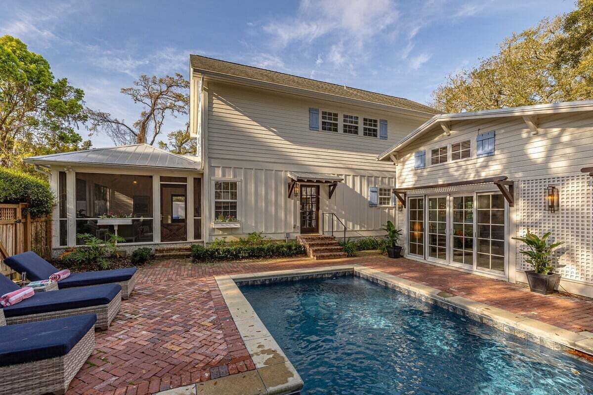 A two-story house with a swimming pool, a covered patio, and a fenced backyard.