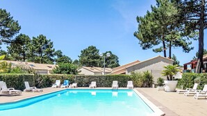 A swimming pool with lounge chairs and a clear sky.