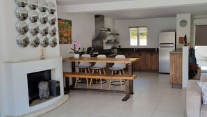 A modern kitchen with a central island, white walls, and a dining area with a wooden bench.