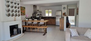 Una cocina moderna con una isla central, paredes blancas y un comedor con un banco de madera.