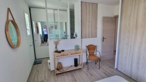A modern bathroom with a mirror, vanity, chair, and wooden flooring.