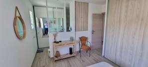 Un baño moderno con espejo, tocador, silla y suelo de madera.
