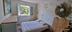 Une chambre à coucher avec un lit, une fenêtre, une peinture murale et un miroir.