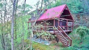 Situated in a forested area, this cabin offers a view of the surrounding trees from its elevated position.