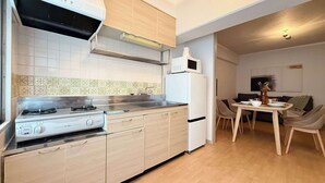 Una cocina moderna con estufa a gas, microondas y refrigerador. Hay un comedor con mesa y sillas.