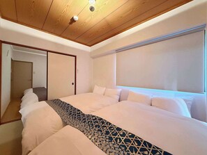 Une chambre d’hôtel avec un grand lit, un plafond en bois et une fenêtre avec des stores.