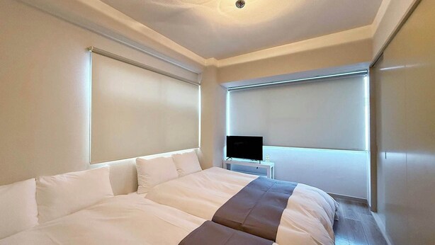 Ein Hotelzimmer mit einem großen Bett, einem Fernseher auf einem kleinen Tisch und einer Deckenleuchte.