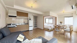 A compact living space with a kitchenette, a sofa, a bed with a view, and a dining area. - Stylish 2-Story Apartment Near Atomic Bomb Dome (Hiroshima)