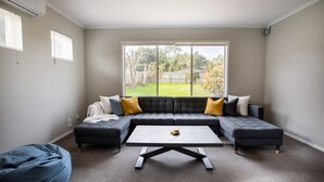 A modern living room with a sectional sofa, a coffee table, and a bean bag. - Daintree Family Getaway- Beach, Aircon, Great yard (Ocean Grove)