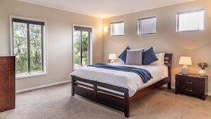 A bedroom with a large bed, two bedside tables, and a dresser. There are three windows providing natural light. - Daintree Family Getaway- Beach, Aircon, Great yard (Ocean Grove)