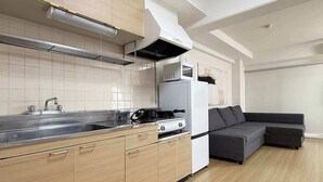 A modern kitchen with a built-in stove, microwave, and oven, a large sink, and wooden cabinets. - Quiet 3BR Near Downtown Kitchen & Dining Equipped (Hiroshima)