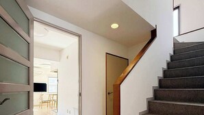 A modern staircase with a wooden handrail leading to a second-floor landing. - Quiet 3BR Near Downtown Kitchen & Dining Equipped (Hiroshima)