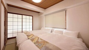 A bedroom with a large bed, a shoji screen door, and a ceiling light. - Quiet 3BR Near Downtown Kitchen & Dining Equipped (Hiroshima)