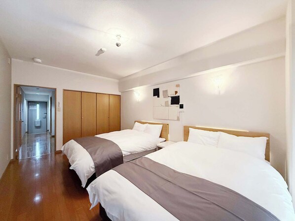 Ein Hotelzimmer mit zwei Betten, einem Holzschrank, einem Gang und einer Wandleuchte.
