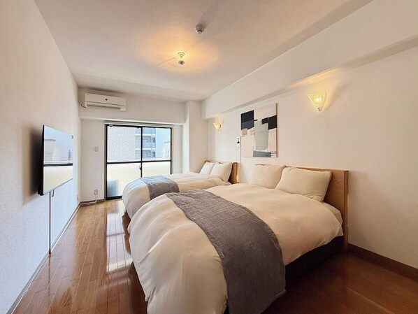 A hotel room with a large bed, a TV, a sliding glass door, and a ceiling light.