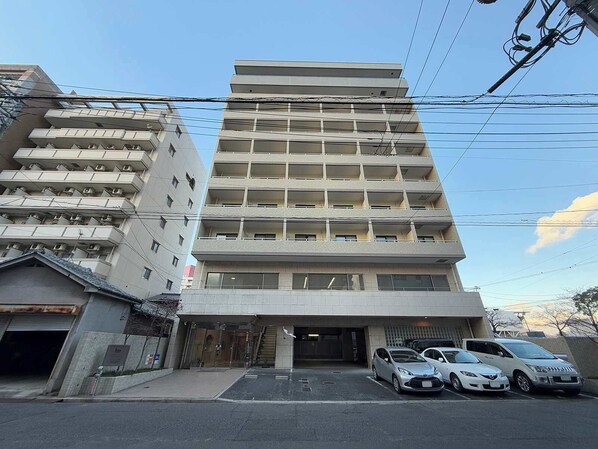 Un hôtel à plusieurs étages, doté d’une entrée principale, d’un espace de stationnement et de plusieurs voitures garées devant.