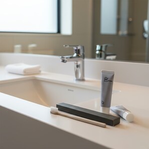 Une salle de bain avec un lavabo blanc, un miroir et un porte-brosse à dents contenant un tube de dentifrice.