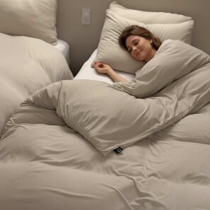 Un lit dans lequel une personne est allongée, recouverte d’une couverture.